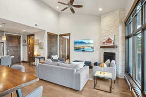 Living area featuring a towering ceiling, visible vents, ceiling fan, and wood finished floors