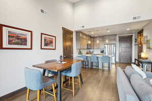 Dining room featuring visible vents, wood finished floors, and a high ceiling