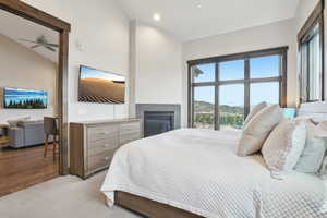 Bedroom with lofted ceiling, a glass covered fireplace, wood finished floors, and recessed lighting