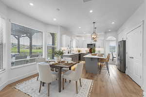 Dining area featuring light wood-style floors, recessed lighting, baseboards, and arched walkways