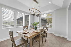 Dining space featuring baseboards, light carpet, an inviting chandelier, and vaulted ceiling