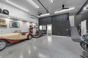 Detached Garage with a wall mounted AC, a garage door opener, and baseboards