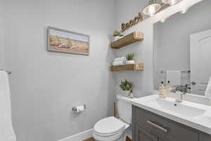 Bathroom featuring toilet, vanity, and baseboards