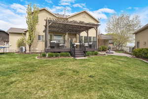 Rear view of property featuring stucco siding, a yard, fence, central AC unit, and a pergola