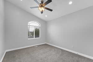 Spare room featuring lofted ceiling, ceiling fan, visible vents, baseboards, and carpet