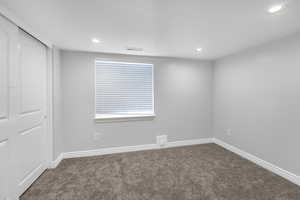Carpeted empty room with visible vents, recessed lighting, and baseboards