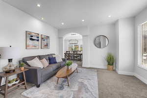 Carpeted living area featuring recessed lighting, arched walkways, and a healthy amount of sunlight