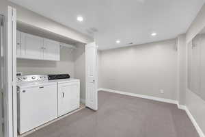 Clothes washing area featuring baseboards, washer and dryer, recessed lighting, light carpet, and laundry area