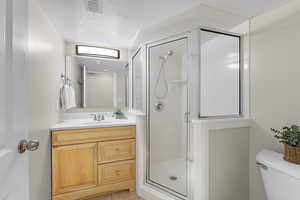 Bathroom with a shower stall, toilet, vanity, visible vents, and a textured ceiling