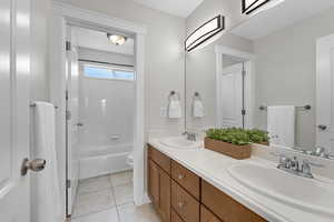 Full bathroom with toilet, tile patterned flooring, double vanity, and a sink