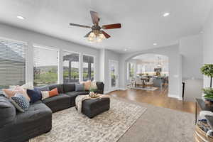 Living area with recessed lighting, arched walkways, ceiling fan, and a healthy amount of sunlight