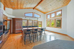 Kitchen featuring high vaulted ceiling, gas stovetop, a breakfast bar area, wood flooring, and recessed lighting