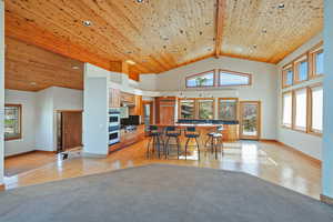 Kitchen featuring wood flooring, stainless steel double oven, exhaust hood, a breakfast bar, and high vaulted ceiling