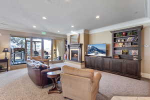 Clubhouse living area featuring light carpet, crown molding, a lit fireplace, and recessed lighting