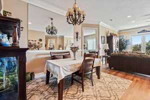 Dining area featuring recessed lighting, ornamental molding,  inviting chandelier & large mirror that expands the dimensions of the room