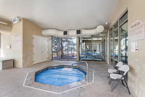 Clubhouse view of swimming pool with an indoor hot tub and a pool