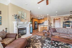 Living room with recessed lighting, ornamental molding, a glass covered fireplace, and ceiling fan with notable chandelier