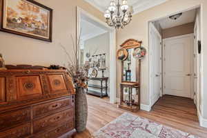 Hall featuring baseboards, an inviting chandelier, crown molding. LVP flooring