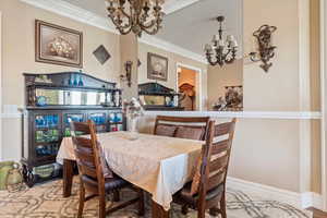 Dining space with ornamental molding and a notable chandelier