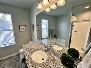 Full bath with a shower stall, a chandelier, toilet, a garden tub, and vanity