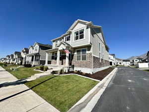 View of front of house featuring a front lawn, a residential view, covered porch, stone siding, and stucco siding