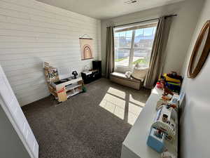 Recreation room featuring visible vents, dark colored carpet, and a textured ceiling