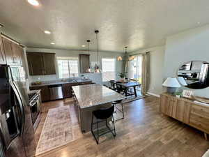 Kitchen with a center island, wood finished floors, a textured ceiling, and appliances with stainless steel finishes