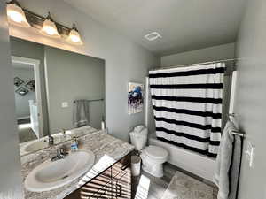 Bathroom with wood finished floors, toilet, vanity, shower / tub combo, and a textured ceiling