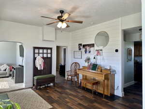 Entryway with arched walkways, ceiling fan, and dark fun wood-style flooring