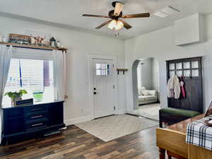 Foyer entrance with country charm, arched walkways, ceiling fan, dark wood-style floors, all simple and warm