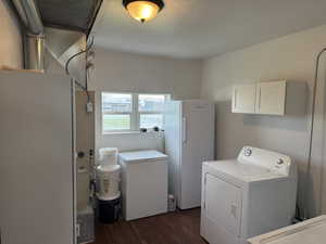 Laundry room with dark wood-style flooring, access to the backyard, cabinet space, and a textured ceiling