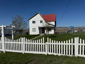 View of the secluded setting of the home featuring metal roof, a fenced front yard, a front lawn, and a playground