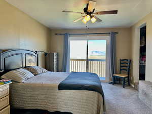 Carpeted bedroom with access to exterior deck and mountain view, a ceiling fan, and baseboards