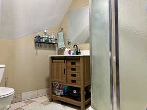 Bathroom with toilet, vanity, a shower stall, and lofted ceiling
