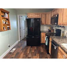 Country kitchen featuring dark stone countertops and fun dark wood-type flooring