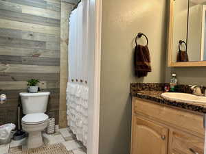 Full updated bathroom with toilet, a shower with curtain, tile patterned flooring, and vanity