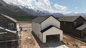 View of side of property with a mountain view, driveway, an attached garage, and roof with shingles