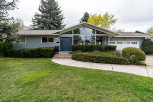 View of front of home featuring driveway, a front lawn, and an attached garage