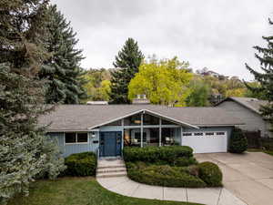 View of front of property featuring fence, roof with shingles, concrete driveway, and an attached garage
