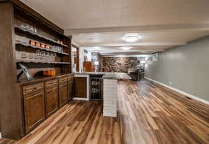 Bar featuring bar, visible vents, wine cooler, baseboards, and wood finished floors