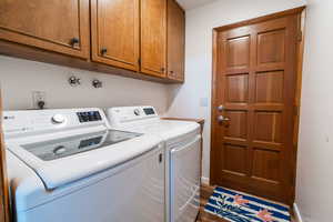 Washroom with wood finished floors, independent washer and dryer, cabinet space, and baseboards