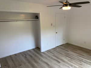 Unfurnished bedroom featuring light wood-style floors, ceiling fan, baseboards, and a closet