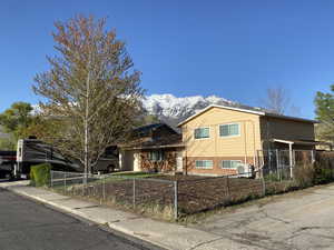 Split level home with a mountain view, central AC unit, a fenced front yard, and brick siding