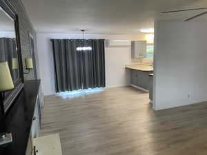 Dining space with light wood-type flooring, an AC wall unit, a notable chandelier, and baseboards