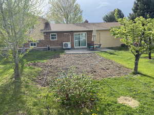Rear view of property featuring brick siding, ac unit, a yard, and a patio area