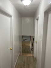 Corridor with a textured ceiling and light wood-style floors