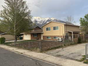 Tri-level home featuring a garage, brick siding, a mountain view, and a fenced front yard