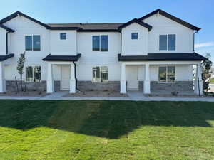 View of front of house with a front lawn and stone siding
