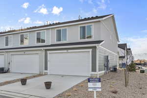 Traditional-style home featuring concrete driveway, central AC unit, and an attached garage