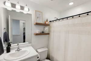 Full bath with toilet, a shower with curtain, and vanity